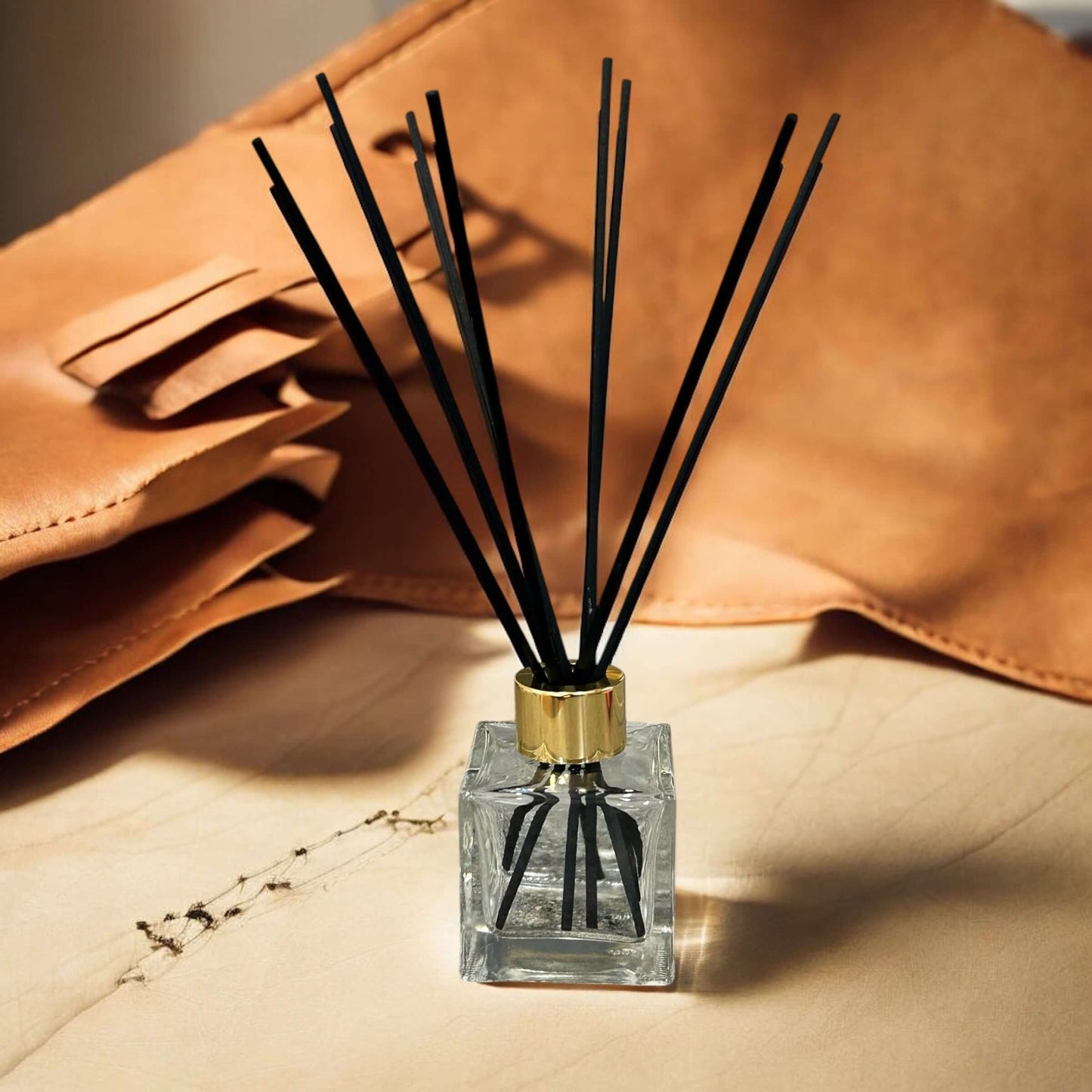 Handmade Cigar Lounge reed diffuser with black reeds in a glass bottle against leather backdrop.