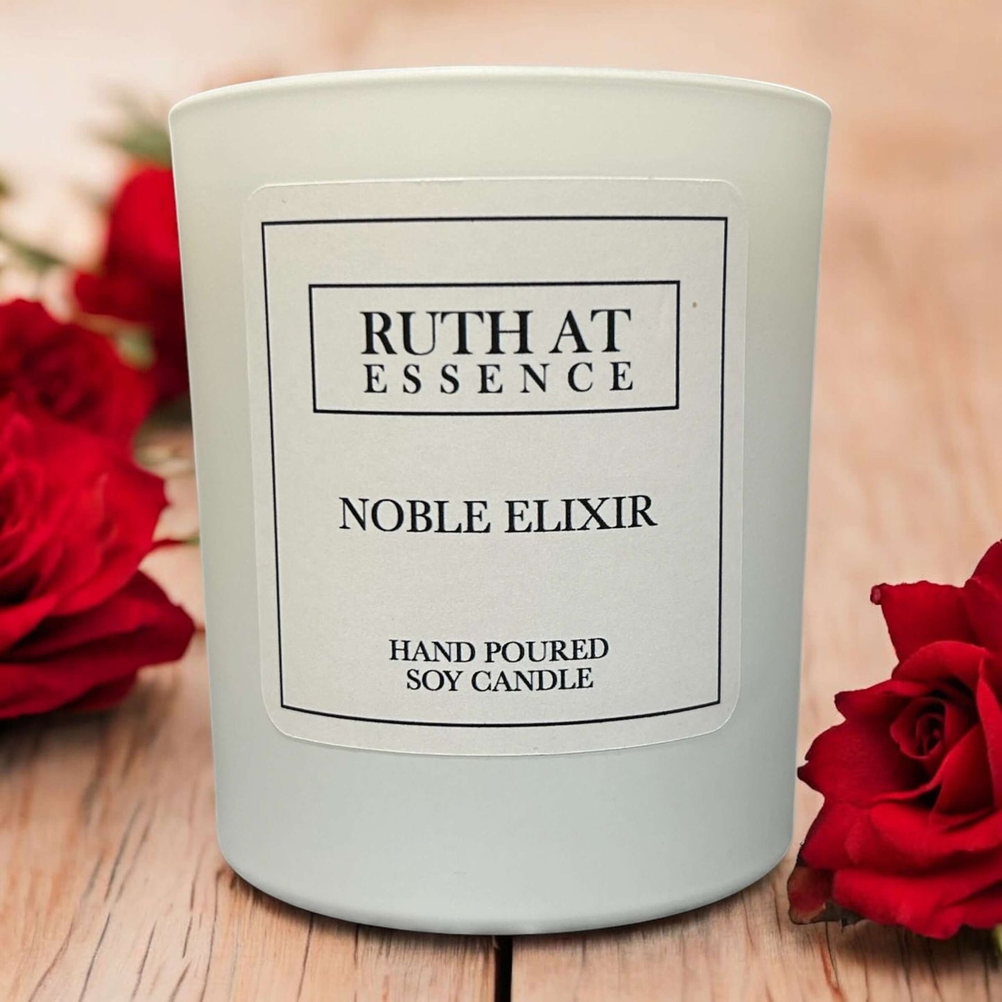 Hand poured vegan friendly Noble Elixir candle with floral notes, surrounded by red roses.