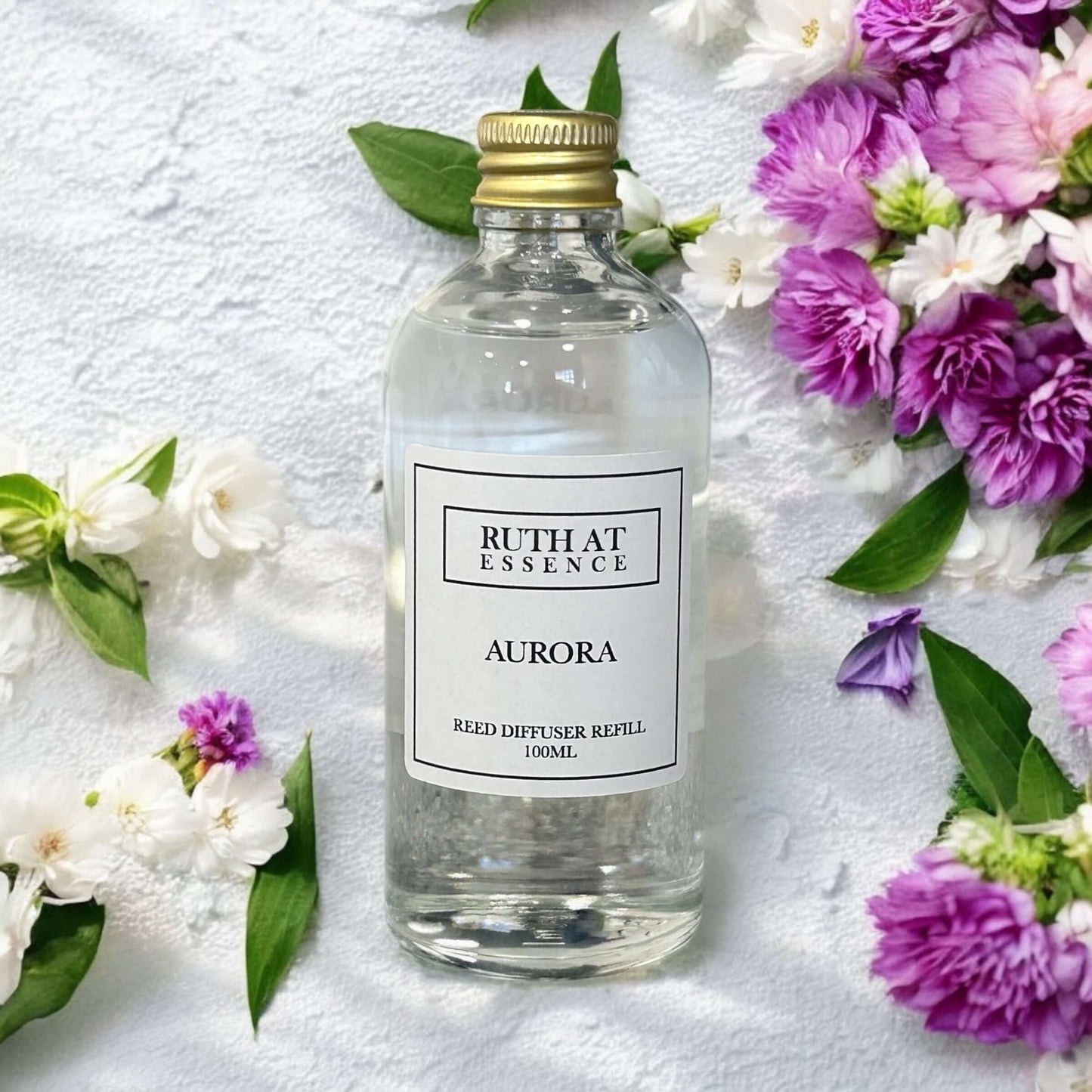 Aurora 100ml diffuser refill surrounded by colorful flowers, vegan friendly and handmade reed diffuser essence.