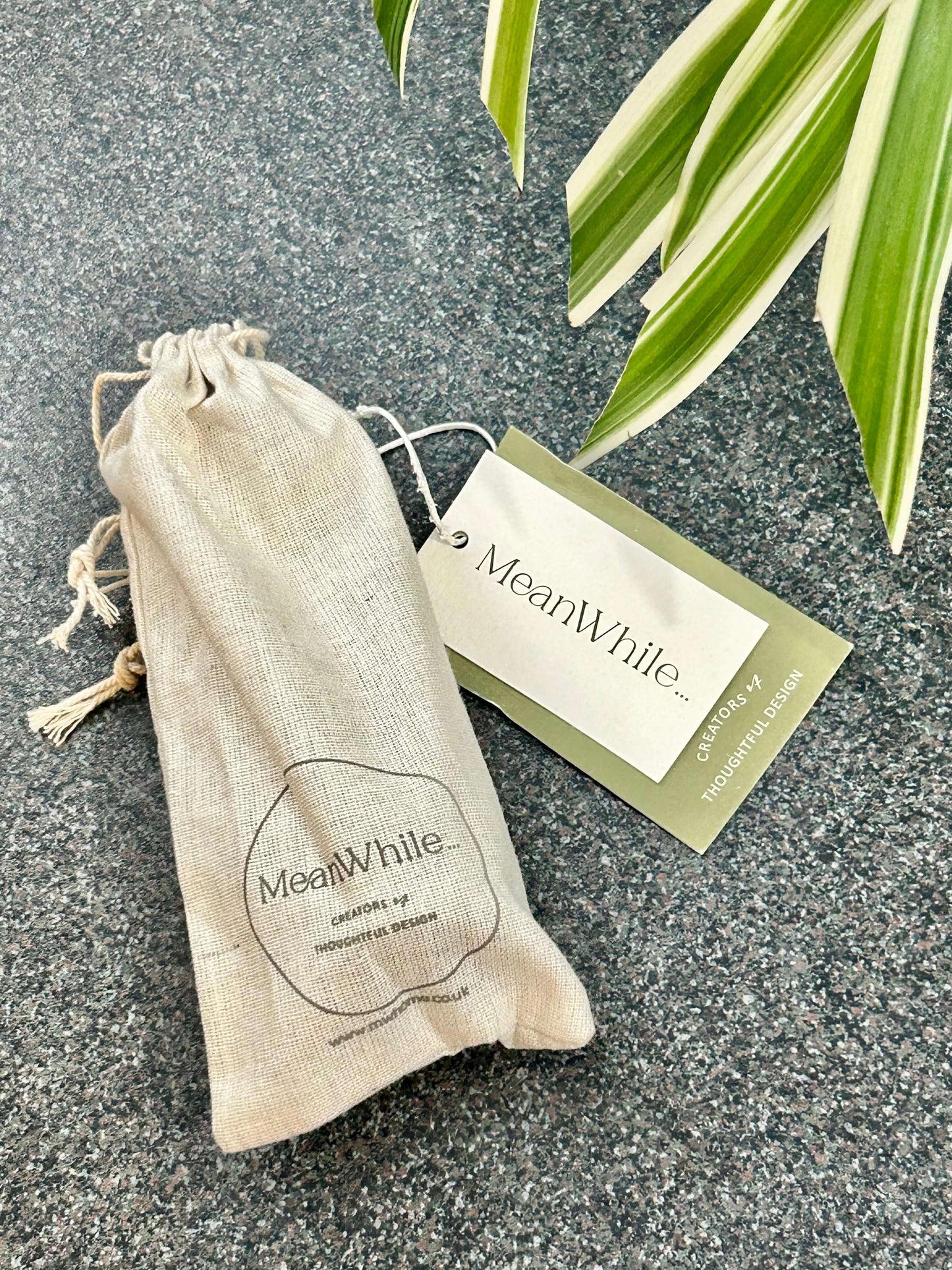 Handmade brass snuffer inside it's cotton pouch with MeanWhile branding.