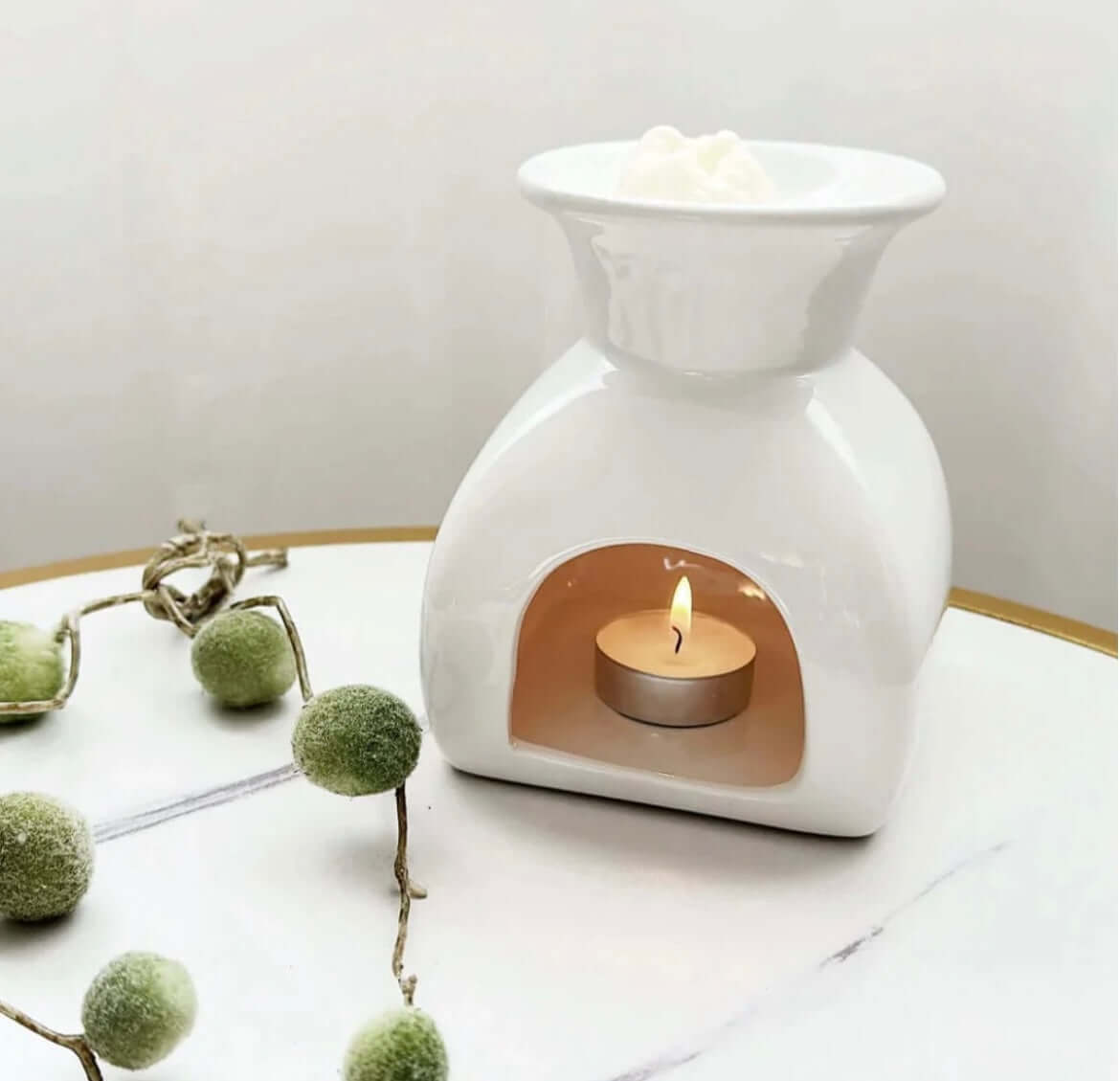 Elegant white wax melt burner with a lit tealight candle, perfect for home fragrance and modern décor.