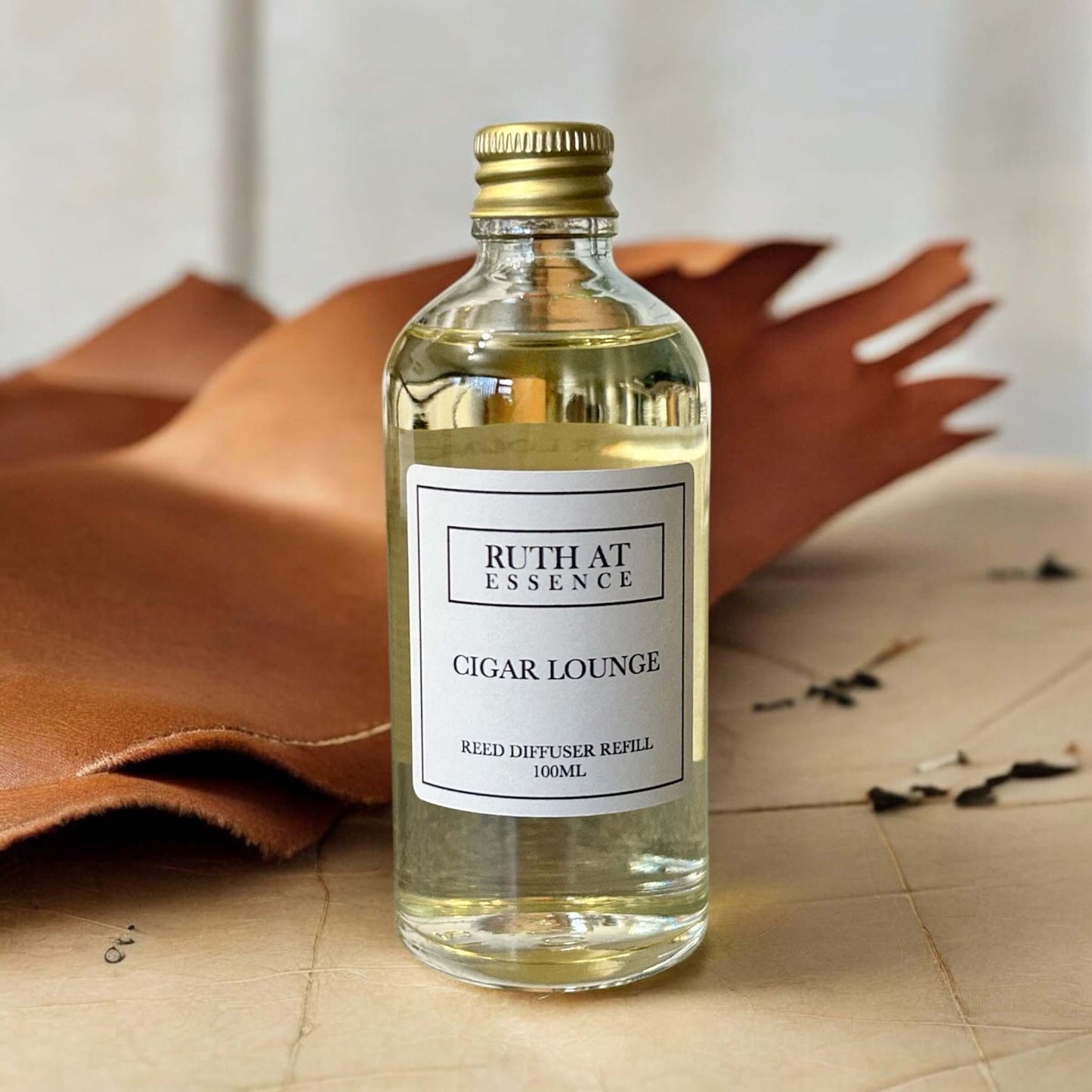 Cigar Lounge reed diffuser refill in 100ml bottle, handmade, vegan-friendly, on leather background.