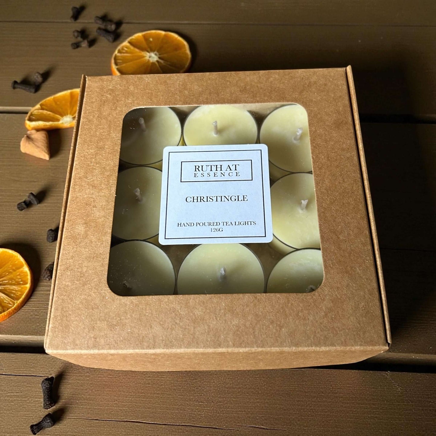Christingle tea lights in a decorative box with orange slices and spices, perfect for creating a cozy holiday atmosphere.