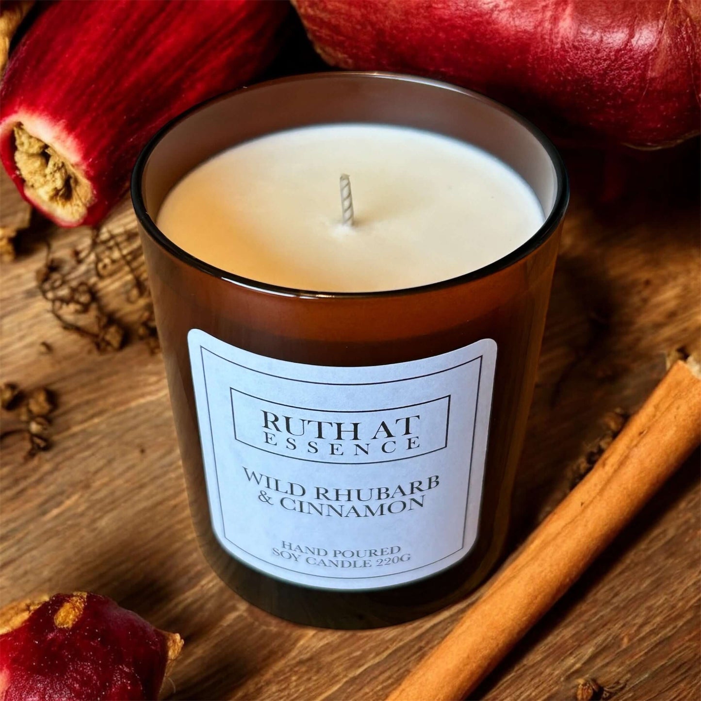 Wild Rhubarb & Cinnamon Candle in a stylish jar surrounded by rhubarb and cinnamon sticks, perfect for festive warmth.