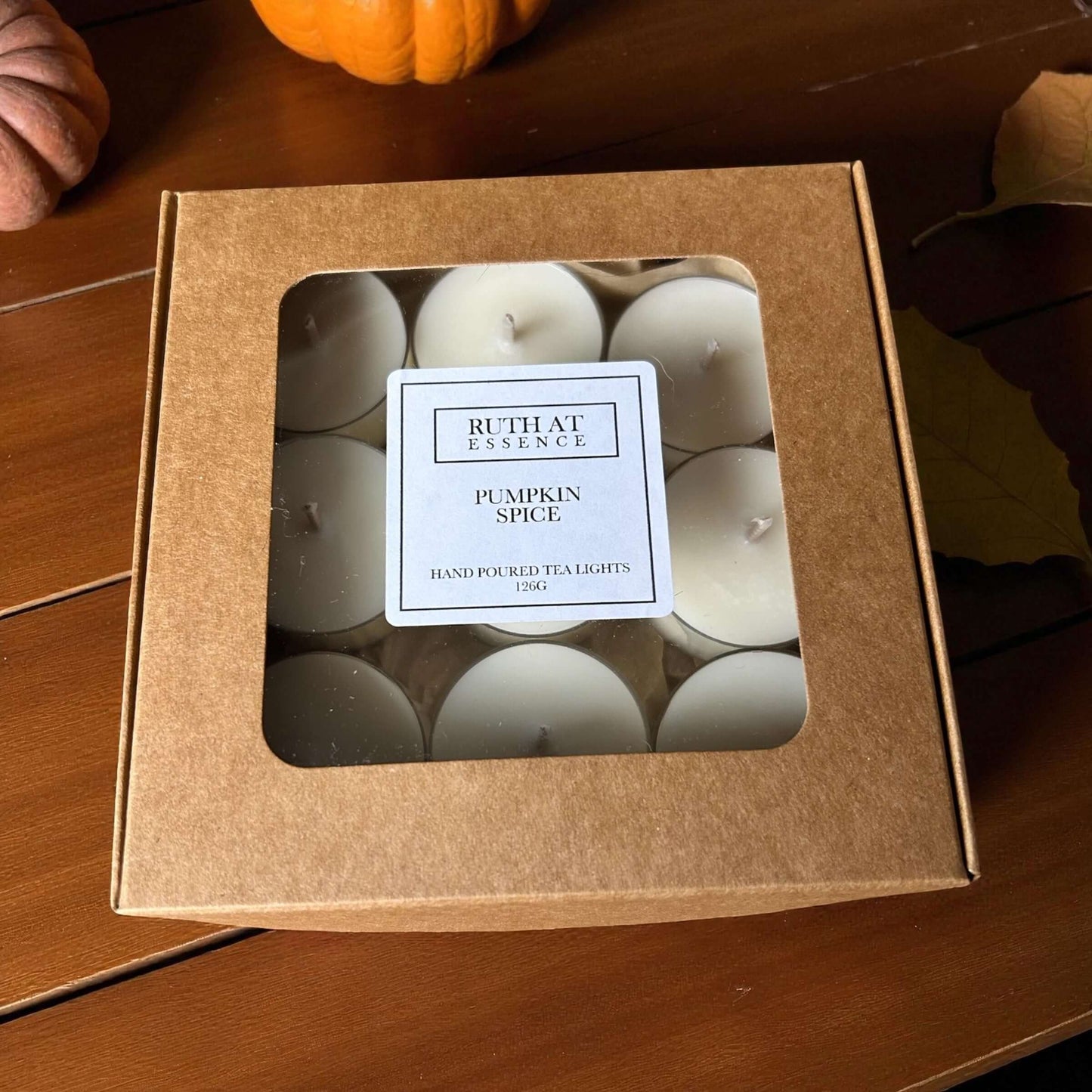 Box of pumpkin spice tea lights from Ruth at Essence with a clear window showcasing the candles inside.