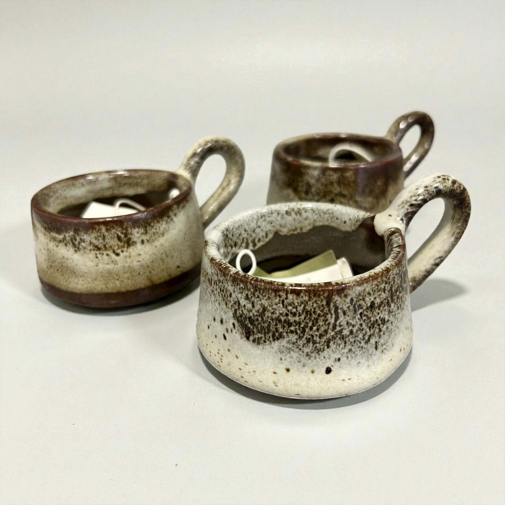 Three handcrafted stoneware mugs with a warm tawny glaze, perfect for tea or cozy home decor.