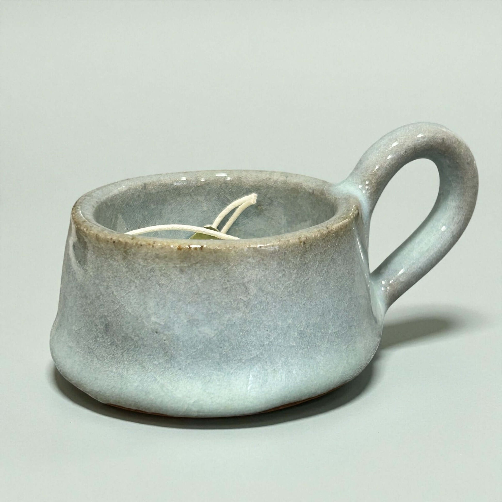 Stylish Stoneware Eggshell Tea-Light Holder designed for a warm glow, featuring a soft eggshell glaze and sweet handle.
