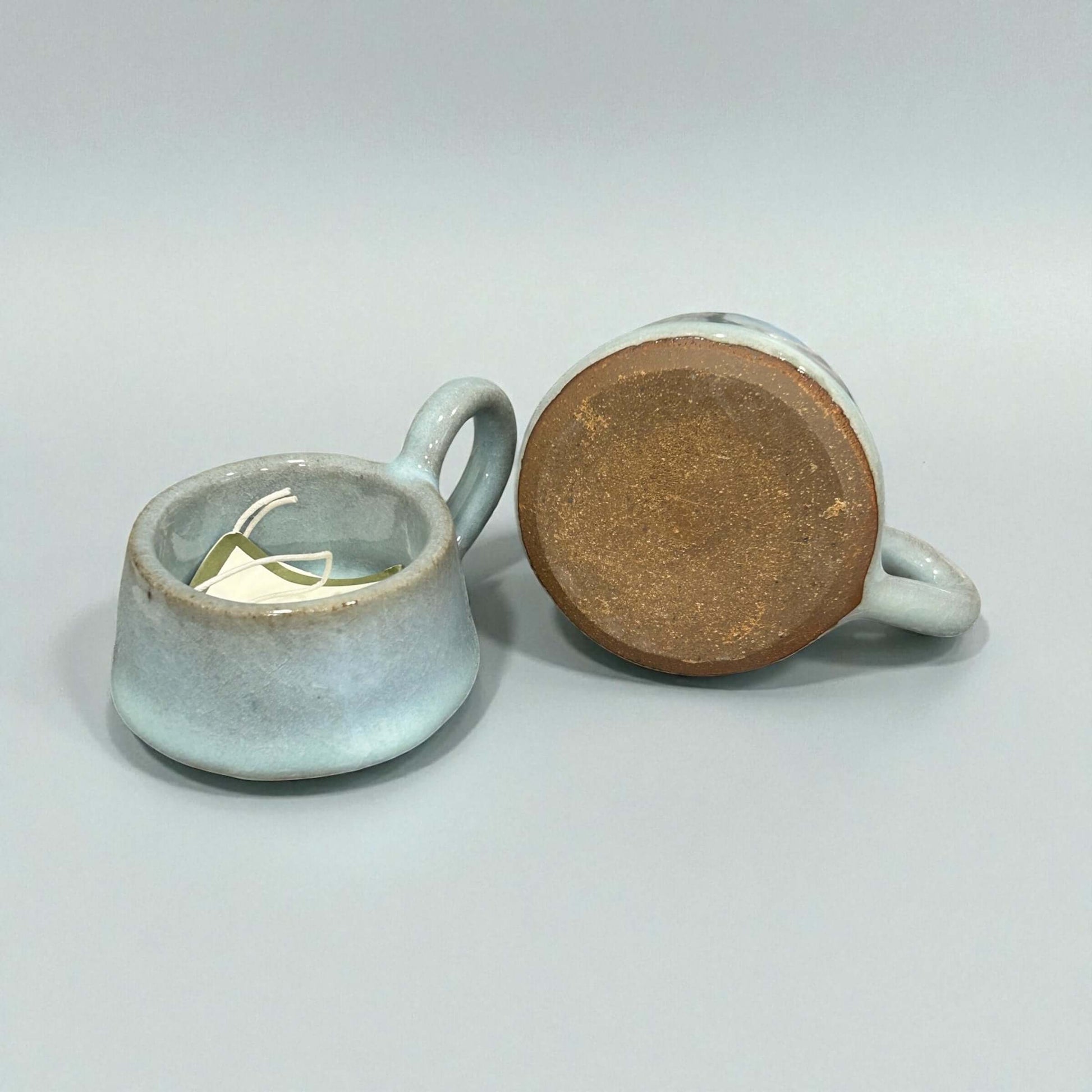 Stoneware Eggshell Tea-Light Holder displayed from multiple angles, showcasing its soft eggshell glaze and handle.